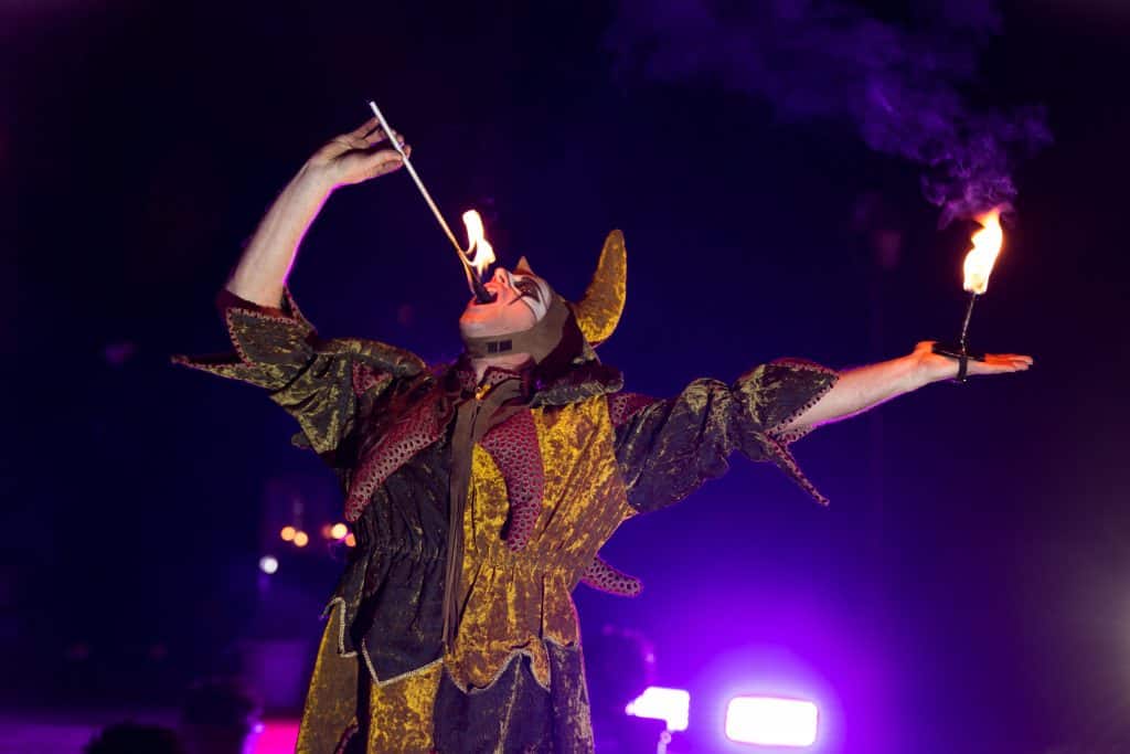 Vuurspuwende nar met brandende fakkels tijdens avondanimatie op evenement